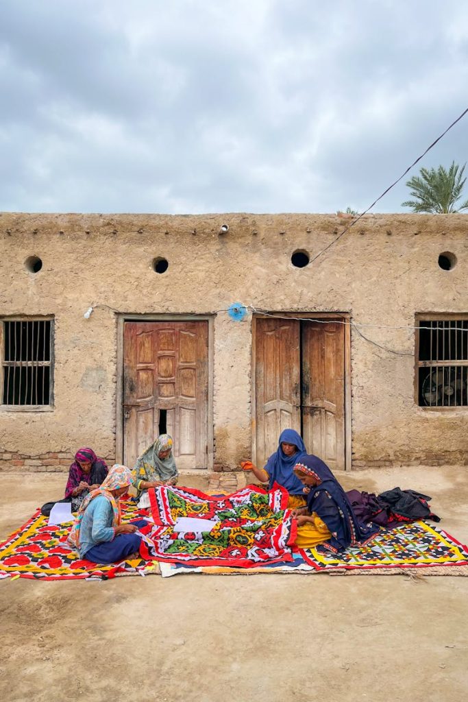 Sindhi women in Sukkur creating vibrant traditional textiles outdoors.